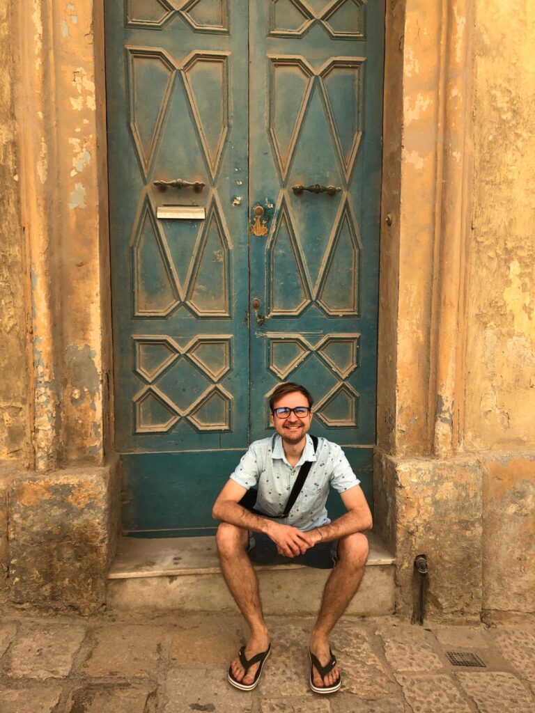 Mężczyzna siedzący przed drzwiami na schodku